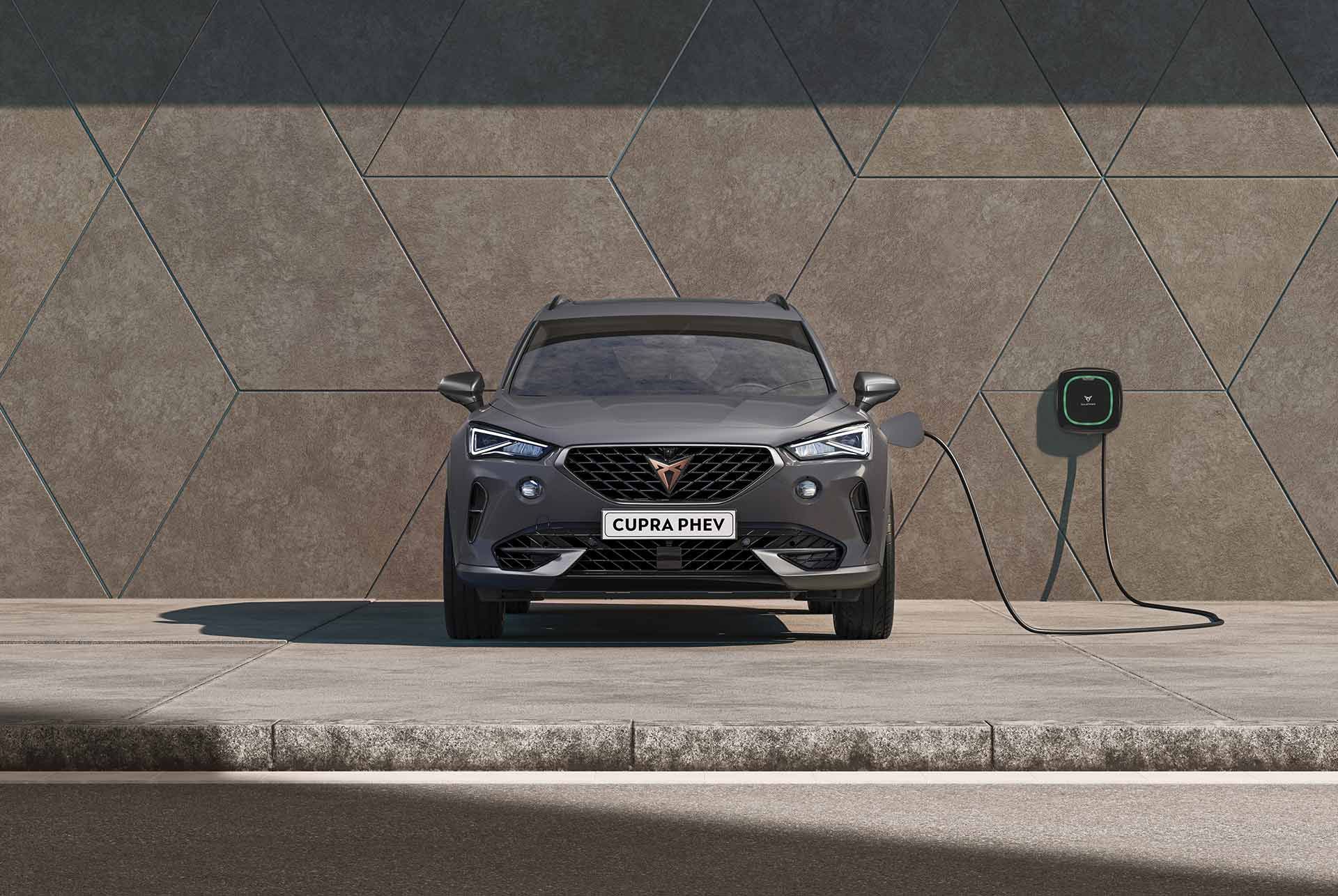 blue 2024 cupra tavascan charging in a car park with an electric car home charging station wall charger